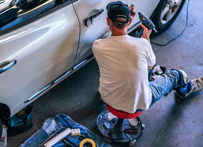 Profissional realizando reparo em carro usado com indício de sinistro na lateral